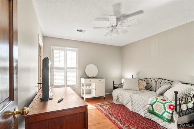 bedroom with wood-type flooring, ceiling fan, and a textured ceiling