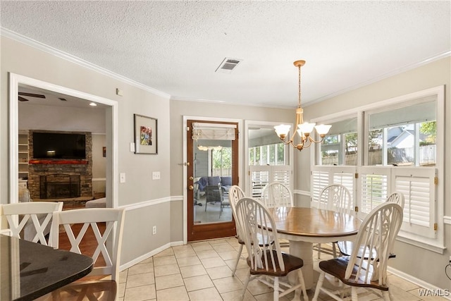 tiled dining room with ornamental molding, a stone fireplace, a textured ceiling, and a notable chandelier