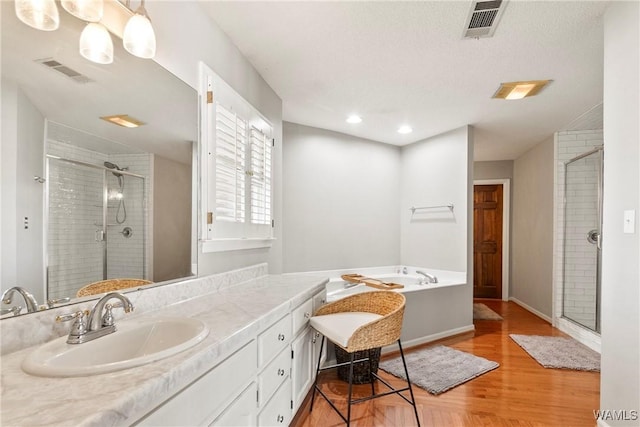 bathroom with shower with separate bathtub, hardwood / wood-style floors, vanity, and a textured ceiling