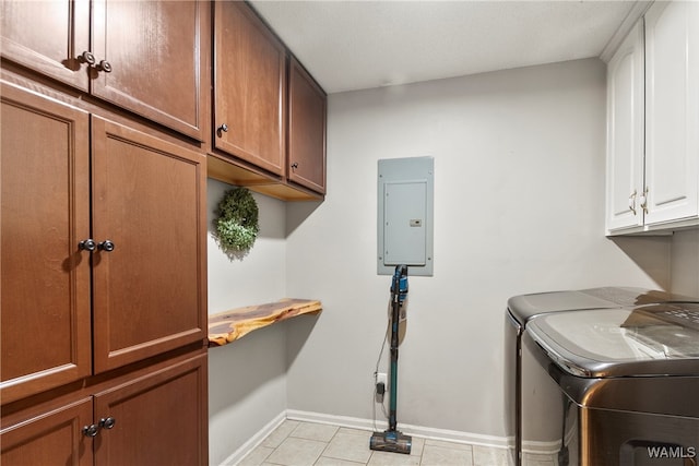 clothes washing area with separate washer and dryer, light tile patterned floors, electric panel, and cabinets