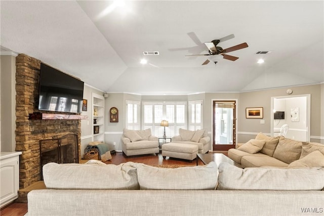 living room with a stone fireplace, built in features, wood-type flooring, lofted ceiling, and ceiling fan