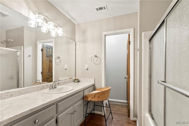 bathroom with vanity, hardwood / wood-style floors, and shower / bath combination with glass door