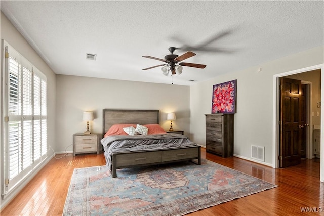 bedroom with multiple windows, wood-type flooring, and a textured ceiling