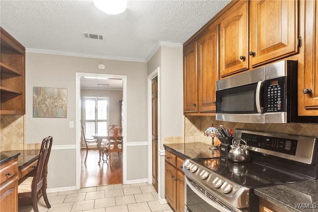 kitchen with light tile patterned floors, ornamental molding, a textured ceiling, and appliances with stainless steel finishes