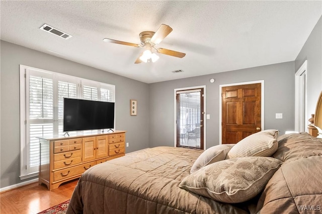 bedroom featuring ceiling fan, hardwood / wood-style flooring, and a textured ceiling