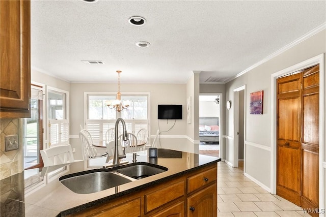 kitchen featuring crown molding, sink, light tile patterned floors, and decorative light fixtures