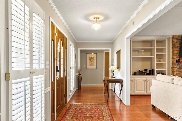 doorway to outside with hardwood / wood-style floors, built in shelves, ornamental molding, and a textured ceiling