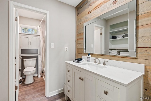 bathroom featuring hardwood / wood-style floors, toilet, vanity, and wood walls