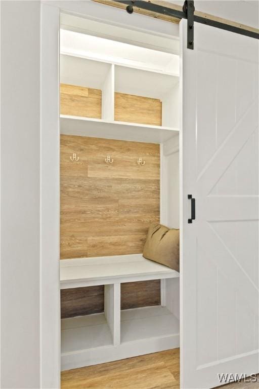 mudroom featuring a barn door and wooden walls