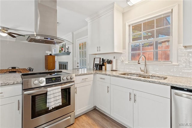 kitchen featuring appliances with stainless steel finishes, white cabinetry, island exhaust hood, sink, and ornamental molding