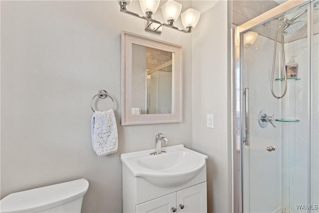 bathroom featuring toilet, vanity, and a shower with door