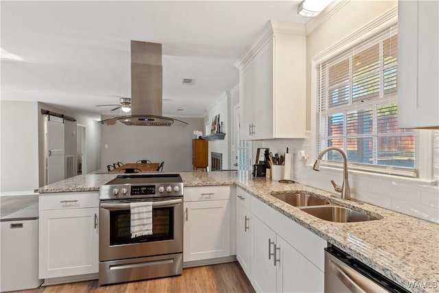 kitchen featuring a barn door, kitchen peninsula, appliances with stainless steel finishes, and island exhaust hood