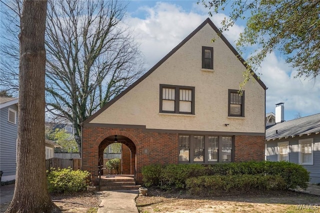 tudor home featuring brick siding and stucco siding