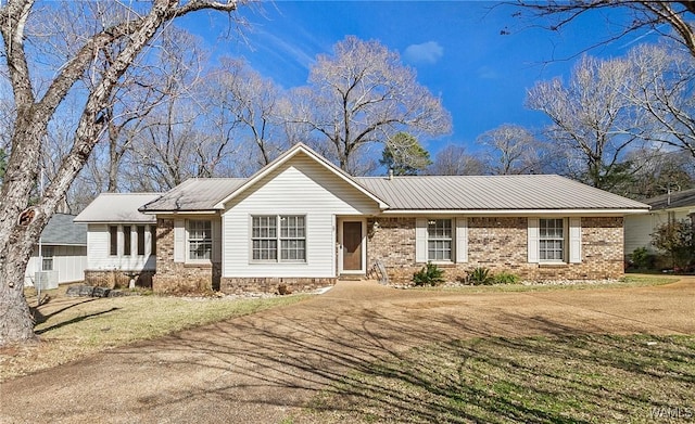 ranch-style house with a front yard, metal roof, and brick siding