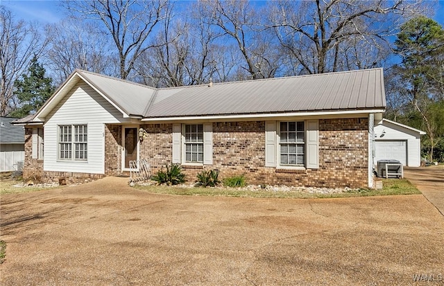 ranch-style house with brick siding, concrete driveway, metal roof, a garage, and an outdoor structure