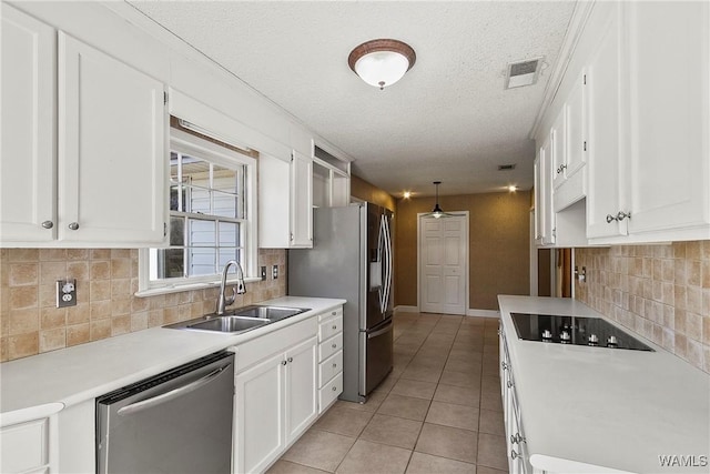 kitchen with light tile patterned floors, appliances with stainless steel finishes, light countertops, white cabinetry, and a sink