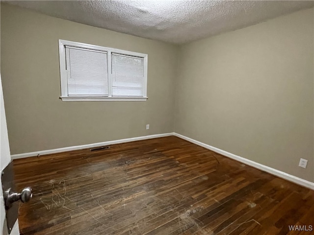 empty room with dark hardwood / wood-style floors and a textured ceiling