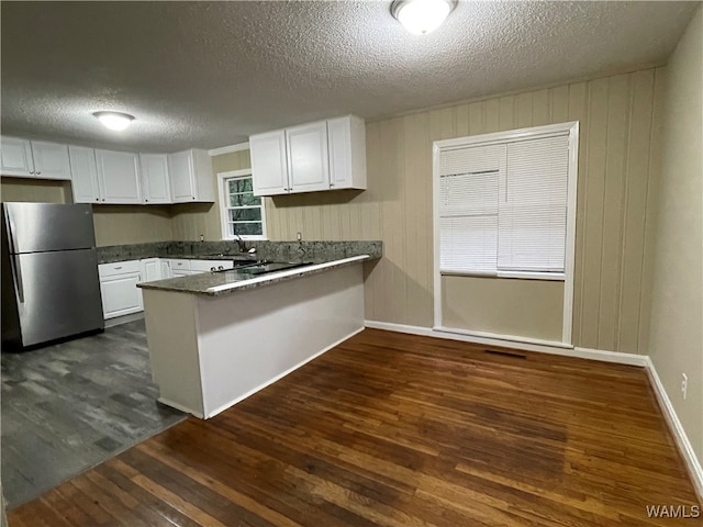 kitchen featuring a textured ceiling, stainless steel refrigerator, white cabinetry, and dark hardwood / wood-style floors