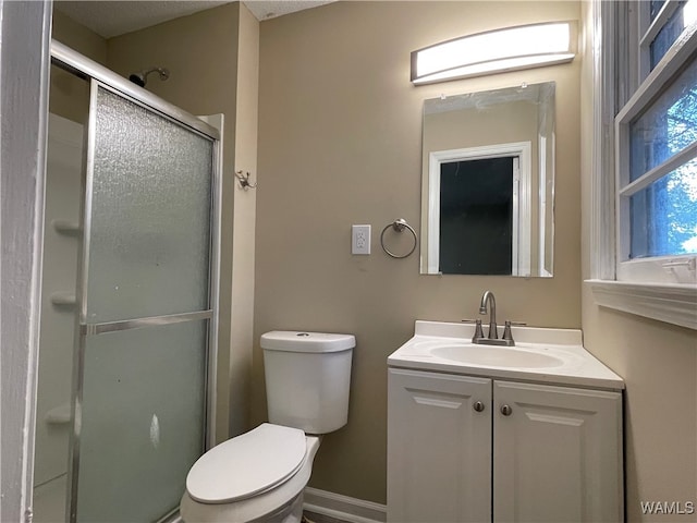 bathroom featuring a shower with door, vanity, and toilet