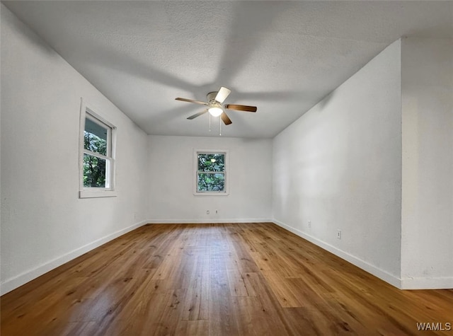 spare room with ceiling fan, plenty of natural light, a textured ceiling, and light wood-type flooring