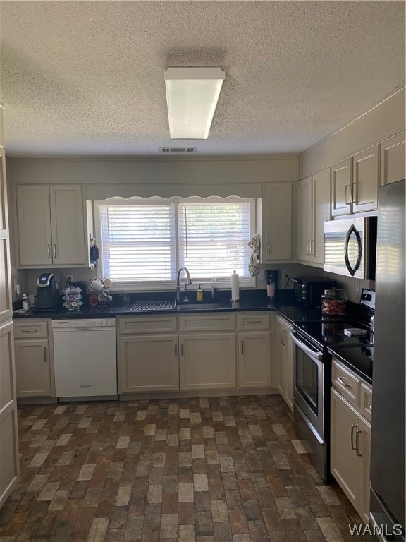 kitchen with white cabinets, sink, stainless steel appliances, and a textured ceiling