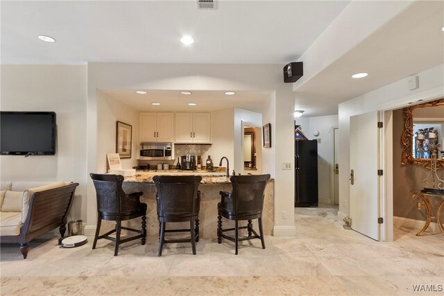 6821 Jade Pt, Tuscaloosa, AL 35406 - kitchen featuring stainless steel microwave, a breakfast bar area, a peninsula, light stone counters, and recessed lighting