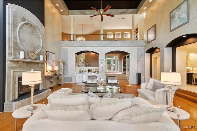 6821 Jade Pt, Tuscaloosa, AL 35406 - living area with arched walkways, a towering ceiling, ceiling fan, wood finished floors, and a premium fireplace