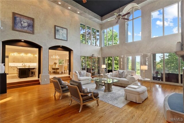 6821 Jade Pt, Tuscaloosa, AL 35406 - living area with arched walkways, a towering ceiling, wood finished floors, a ceiling fan, and a chandelier