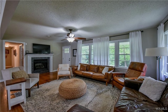 4402 Lakeshore Dr, Northport, AL 35473 - living area featuring a textured ceiling, wood finished floors, a tile fireplace, and ceiling fan