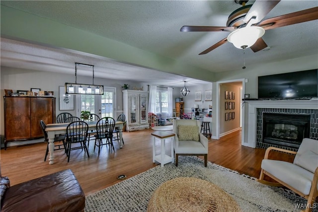 4402 Lakeshore Dr, Northport, AL 35473 - living area featuring a tile fireplace, wood finished floors, ceiling fan, and a textured ceiling