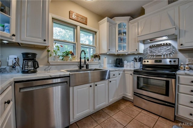 4402 Lakeshore Dr, Northport, AL 35473 - kitchen featuring appliances with stainless steel finishes, light countertops, light tile patterned flooring, custom exhaust hood, and white cabinets