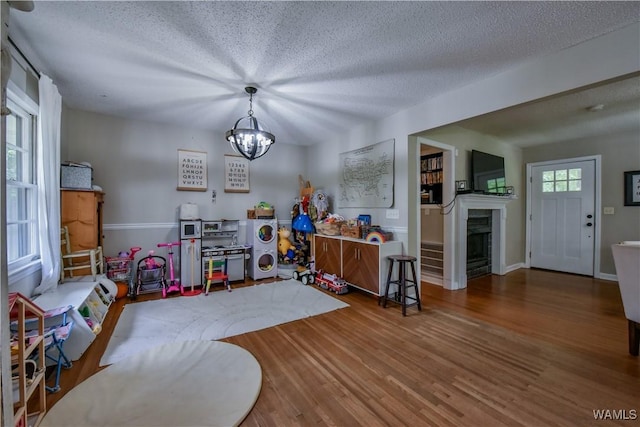 4402 Lakeshore Dr, Northport, AL 35473 - playroom with a fireplace, a chandelier, wood finished floors, and a textured ceiling