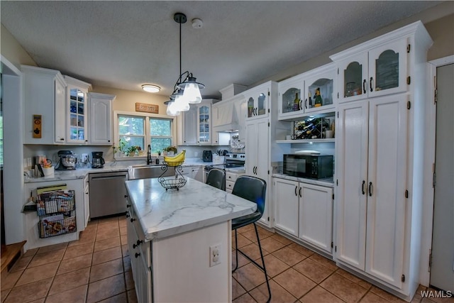 4402 Lakeshore Dr, Northport, AL 35473 - kitchen featuring appliances with stainless steel finishes, light tile patterned flooring, white cabinets, a center island, and a breakfast bar