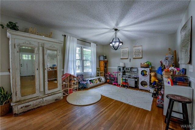 4402 Lakeshore Dr, Northport, AL 35473 - game room with wood finished floors, a chandelier, and a textured ceiling