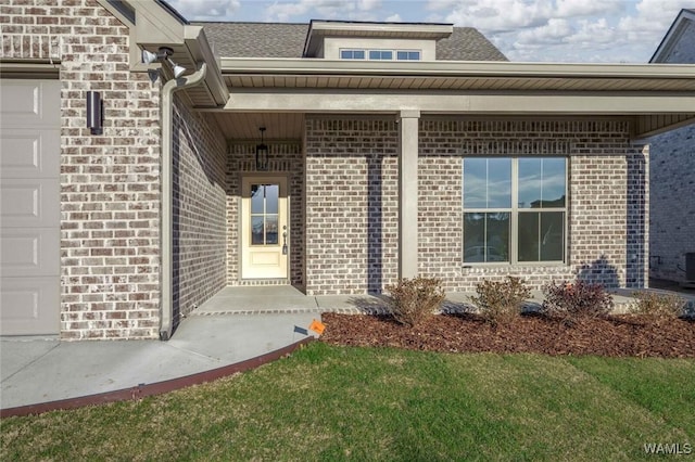 doorway to property featuring a shingled roof, brick siding, and an attached garage