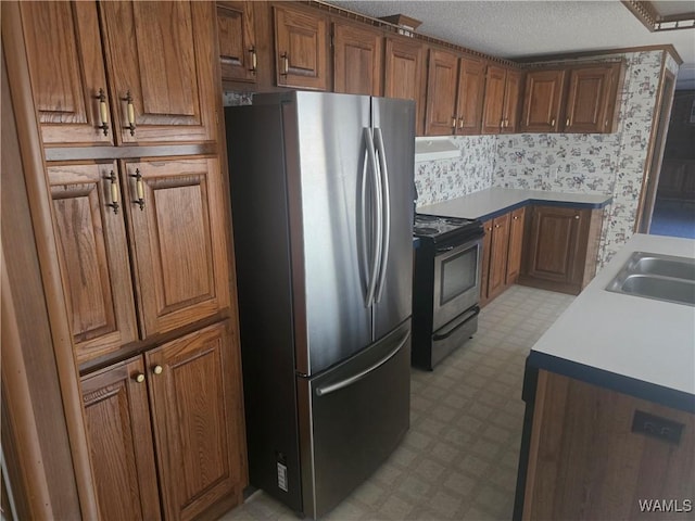 kitchen with appliances with stainless steel finishes, sink, and a textured ceiling