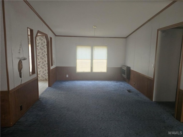 carpeted empty room featuring wood walls, ornamental molding, and an AC wall unit