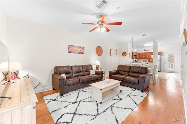 living room with visible vents, baseboards, ceiling fan, ornamental molding, and light wood-style floors