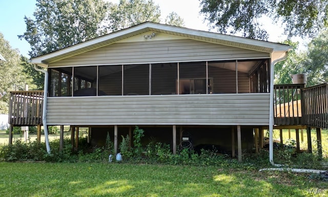 rear view of house with a yard, a sunroom, and a deck