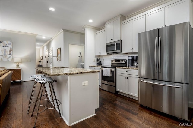 kitchen featuring dark wood finished floors, light stone countertops, appliances with stainless steel finishes, a sink, and crown molding