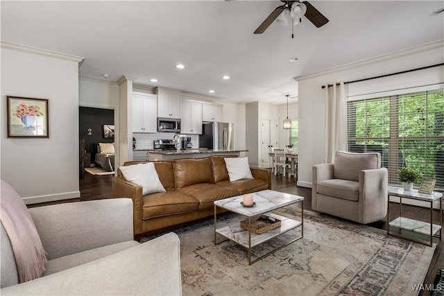 living room with baseboards, recessed lighting, light wood finished floors, ornamental molding, and a ceiling fan