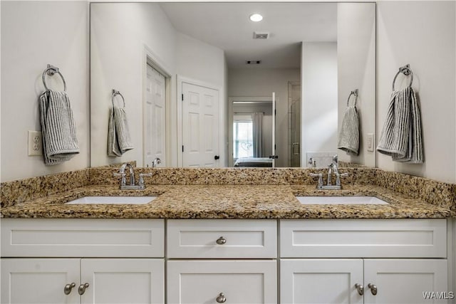 bathroom featuring visible vents, double vanity, and a sink