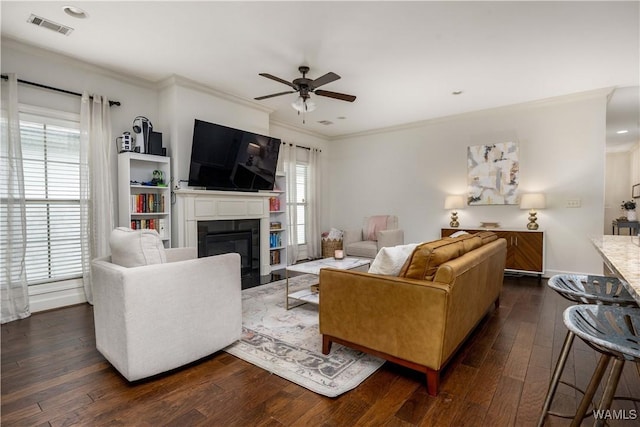 living room featuring a fireplace with flush hearth, a healthy amount of sunlight, a ceiling fan, and ornamental molding