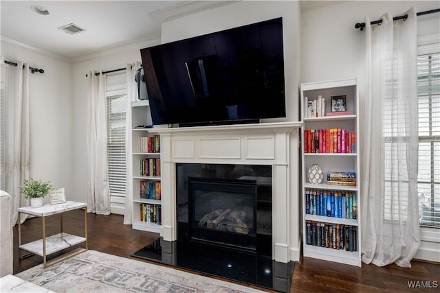 living area featuring visible vents, wood finished floors, crown molding, and a glass covered fireplace