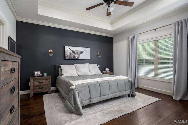 bedroom with crown molding, dark wood-style floors, and a tray ceiling