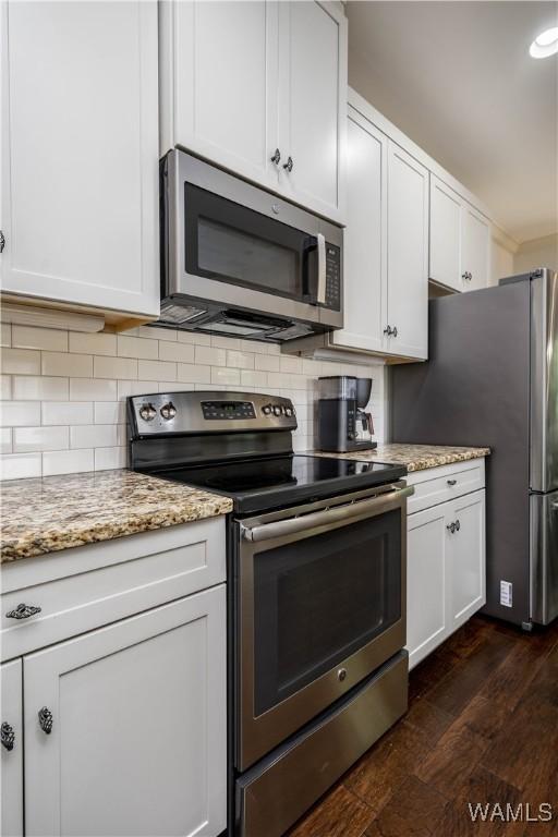 kitchen featuring dark wood-style floors, light stone countertops, appliances with stainless steel finishes, and tasteful backsplash