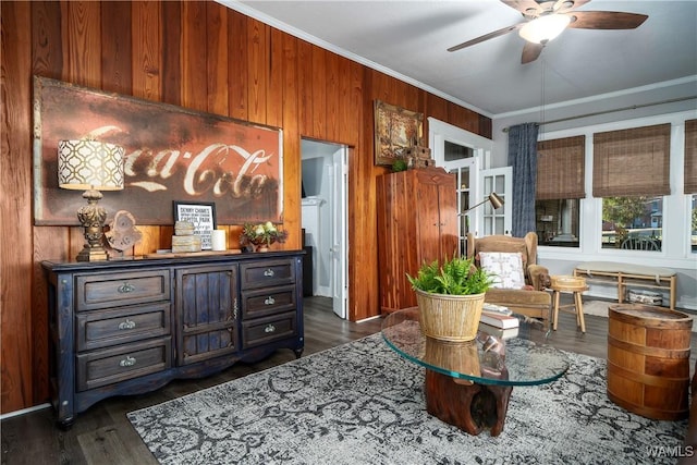 sitting room with ornamental molding, dark hardwood / wood-style floors, ceiling fan, and wood walls