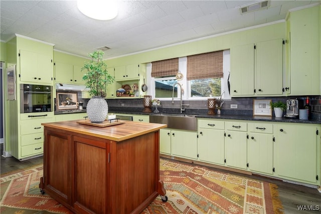 kitchen featuring sink, tasteful backsplash, stainless steel oven, ornamental molding, and dark hardwood / wood-style flooring