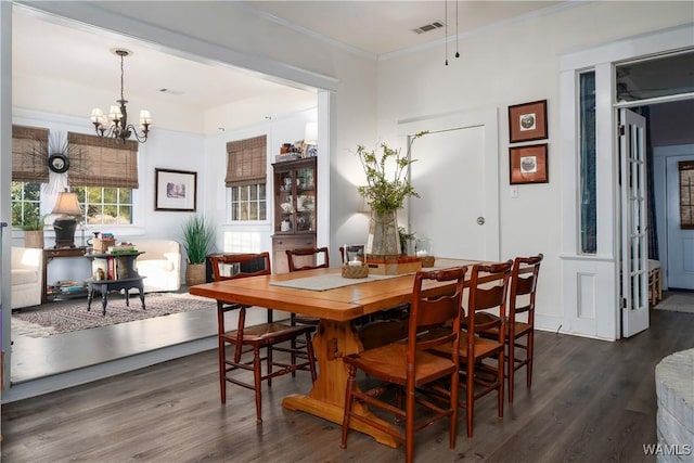 dining room with crown molding, dark wood-type flooring, and a chandelier