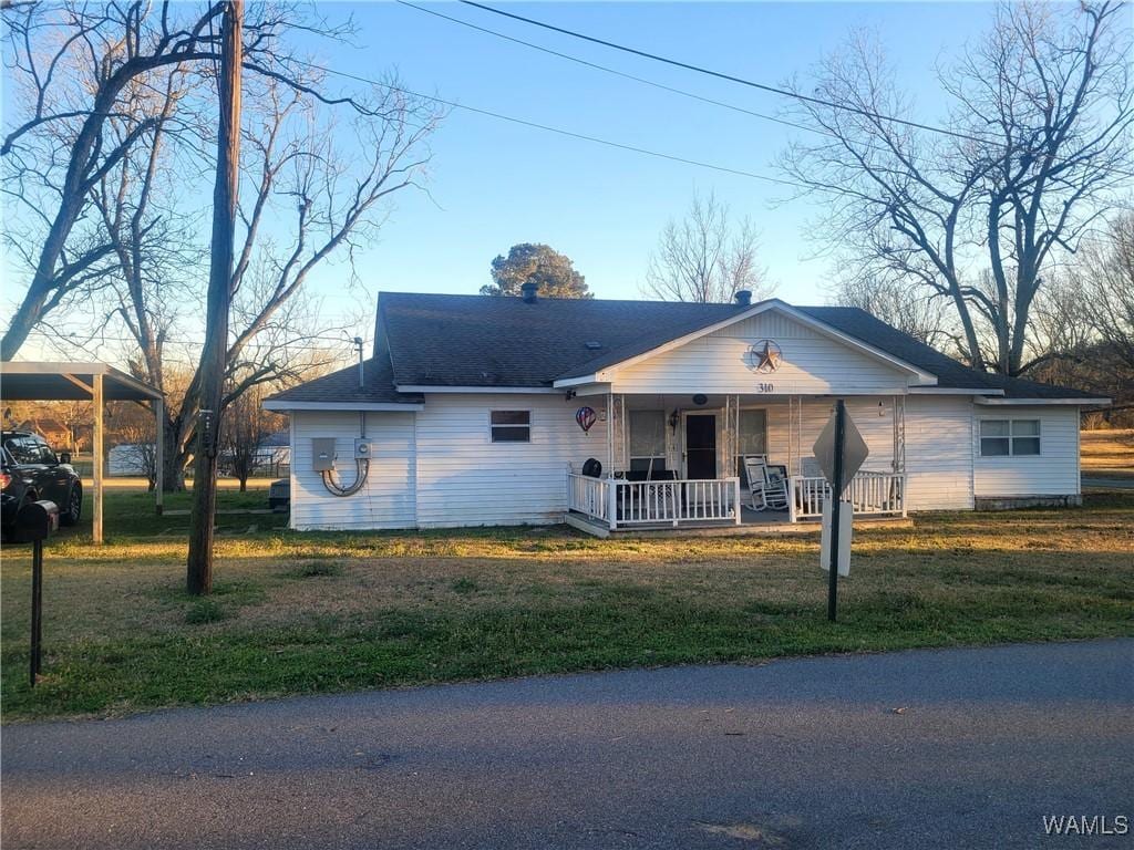 ranch-style home featuring covered porch and a front lawn